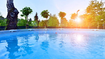 Garden of a suburban house in summer in which you can see a removable swimming pool, pergola in a place with a lot of vegetation.