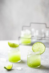 A vibrant and colorful image of two green cocktail shots, each perfectly garnished with a slice of lime.