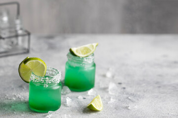 Two perfectly crafted cocktail shots sit ready to be enjoyed, with their salt rims and lime garnishes.