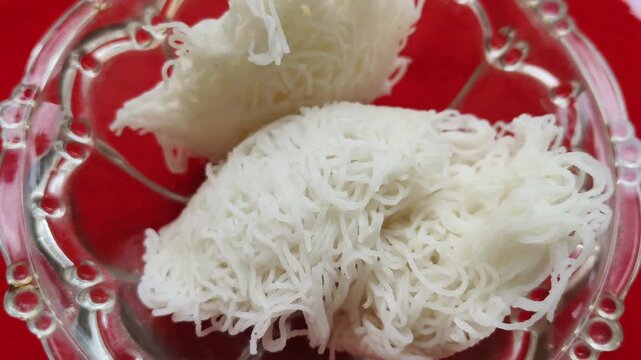 Steamed rice cake Idiyappam, string hopper or noolappam popular traditional vegetarian dish for breakfast and dinner in south Indian states Karnataka, Tamil Nadu and Kerala. Closeup macro top view.
