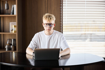Young person focused on laptop in modern workspace during daytime