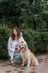 Woman and golden retriever rest in park near rowan tree.