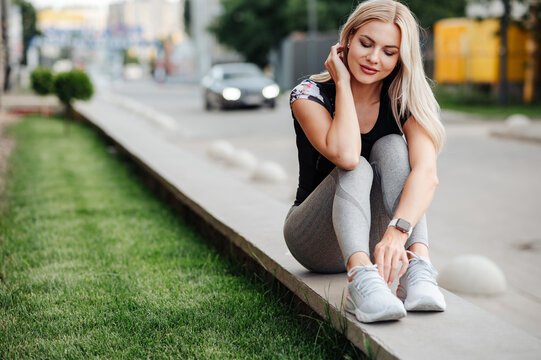 Woman in sport clothes resting on street after cycling