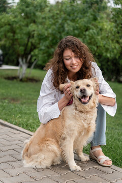 Happy woman hugging golden retriever in park.