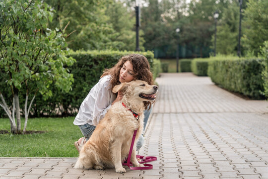 Happy woman hugging golden retriever in park.