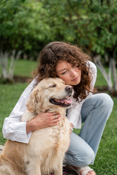 Happy woman hugging golden retriever in park.