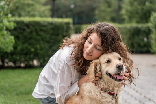 Happy woman hugging golden retriever in park.