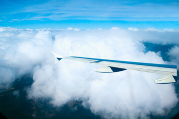 Airplane wing close-up, airplane flying over clouds high in the sky, aerial view from the airplane window