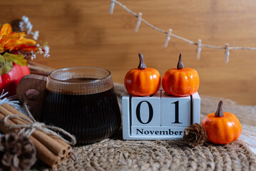 Autumn scene with pumpkins and rustic decor featuring November 1 wooden block calendar. Seasonal stock for fall and Halloween themes. 