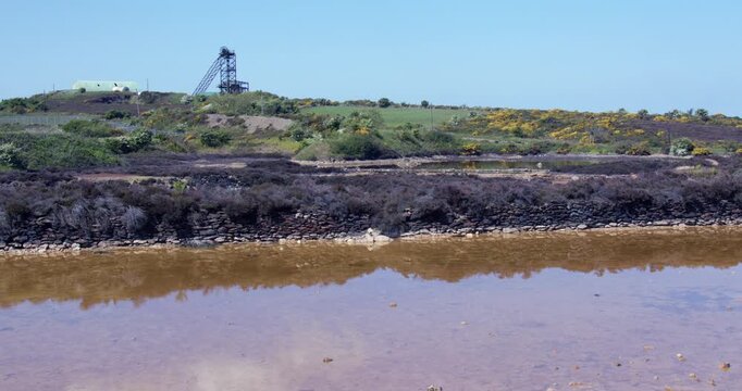 Wide shot of the sampling pool with headframe or headgear in background at mynydd parys mountain copper mine.