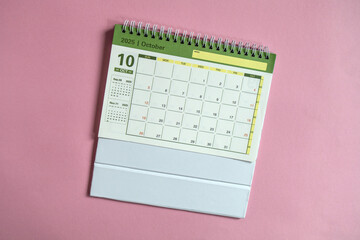 Desktop calendar for October 2025 on a pink background, with copy space.