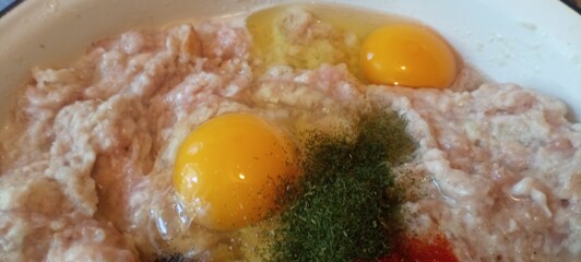 Raw minced meat with eggs and spices for cooking. Meat mixture preparation with seasoning and eggs. Fresh minced meat, eggs and pepper for cutlets. Cooking ingredients in bowl – meat, eggs and herbs	
