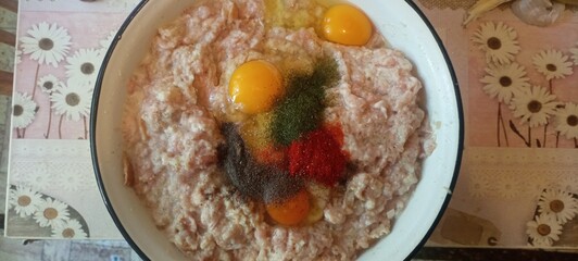 Raw minced meat with eggs and spices for cooking. Meat mixture preparation with seasoning and eggs. Fresh minced meat, eggs and pepper for cutlets. Cooking ingredients in bowl – meat, eggs and herbs