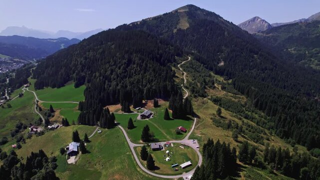 Lush green French Alps tourist destination top of Mont Chery slopes near Les Gets village with rocky mountain tops behind against a clear blue sky