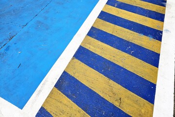 A blue and yellow striped road marking with a solid blue area likely designates a specialized parking zone.