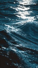 A close-up view of a dark blue ocean, showcasing the intricate patterns of waves and glistening sunlight reflecting on the water's surface.