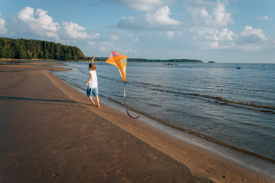 Boy running with kite along shoreline