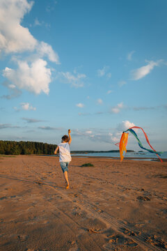 Small child running with kite on sandy beach