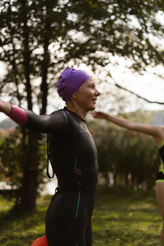 Smiling woman in a wetsuit preparing for water sports outdoor