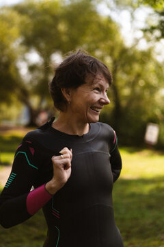 Smiling woman in a wetsuit preparing for water sports outdoor
