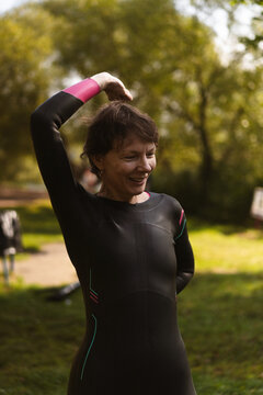 Smiling woman in a wetsuit preparing for water sports outdoor