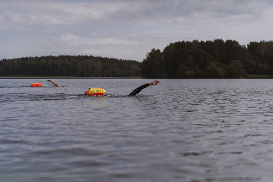A swimmer swims in open water on a calm lake at dawn