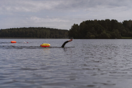 A swimmer swims in open water on a calm lake at dawn