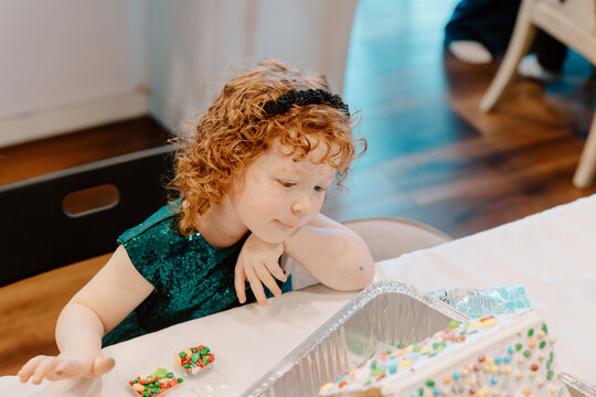 Curious little girl watching colorful candy house creation