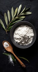 Bowl of flour with olive branch on dark surface