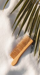 Light beige wooden comb on a white blanket with palm fronds