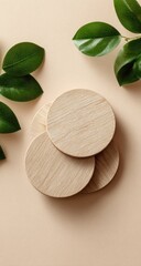 Three light-colored wooden discs layered on a beige background, with green leaves in the corners