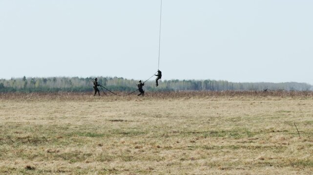 Three paratroopers descend from a helicopter onto a field using a landing rope. Parachuteless landing in the special forces army. Copy space for text