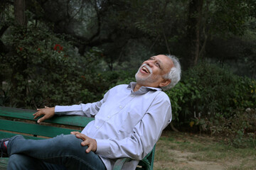 Obraz premium Indian happy senior man feels freedom, fun and spending leisure time while looking at the camera at the park after retirement