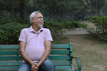 Fototapeta premium Indian happy senior man feels freedom, fun and spending leisure time while looking at the camera at the park after retirement