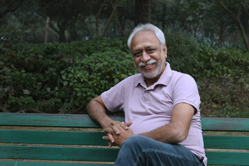 Fototapeta premium Indian happy senior man feels freedom, fun and spending leisure time while looking at the camera at the park after retirement