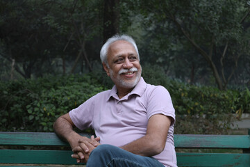 Obraz premium Indian happy senior man feels freedom, fun and spending leisure time while looking at the camera at the park after retirement