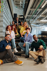 Diverse business team sitting on stairs in modern office
