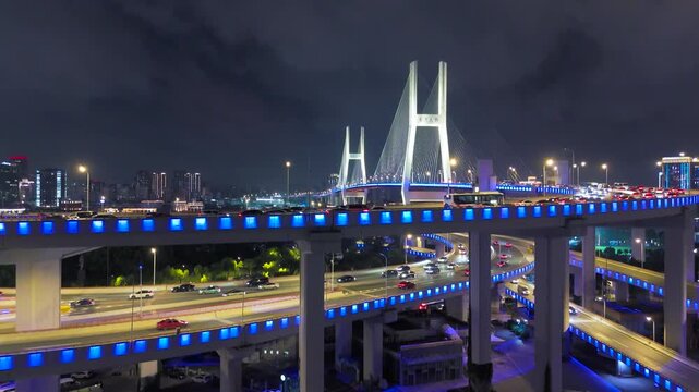 Aerial illuminated elevated highways and the Nanpu Bridge at night with busy traffic in Shanghai, China.