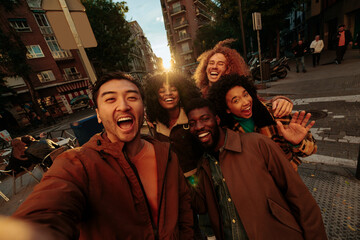 Happy multiracial friends taking photo of themselves while walking down the street