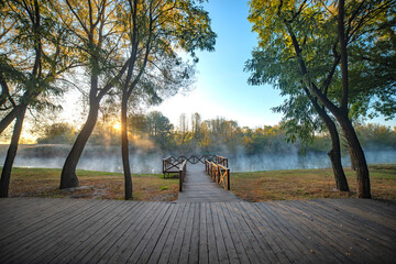 Autumn park by the river with fog.