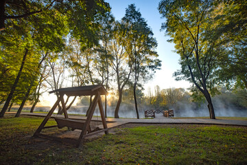 Autumn park by the river with fog.