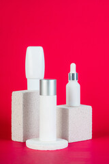 Cosmetic product in tube, bottle, lotion or serum with stylish props on red background. 