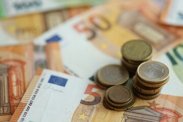 Stacks of euro cent coins lien on big amount of euro banknotes