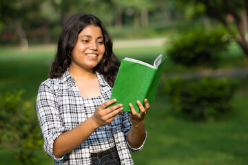 Indian smart student girl studying at park with books, laptop and notebooks . Indian student educational young teenager girl at park outside campus 