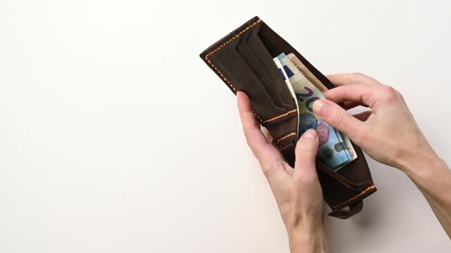 Сlose up of female hands counting money bills in a wallet on a white table. 
