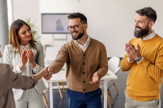 Colleagues Shaking Hands in Modern Office Setting with Smiling Faces and Bright Atmosphere