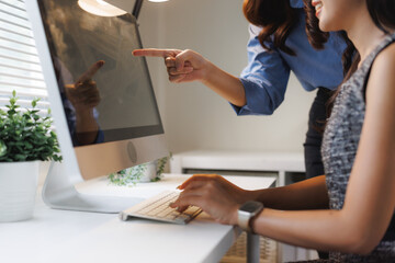 Businesswomen collaborating on computer, discussing work strategy