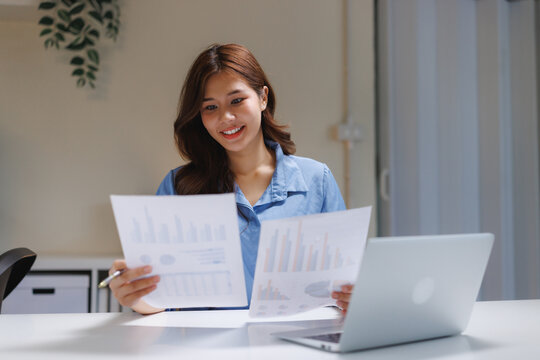 Happy woman analyzing business data reports at desk - Powered by Adobe