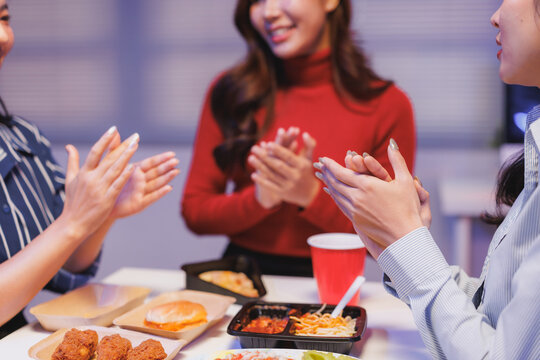 Coworkers applauding during office celebration with takeaway food
