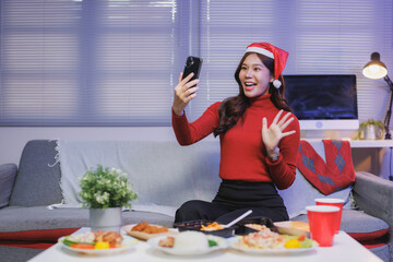 Asian woman celebrating christmas video calling friends at home